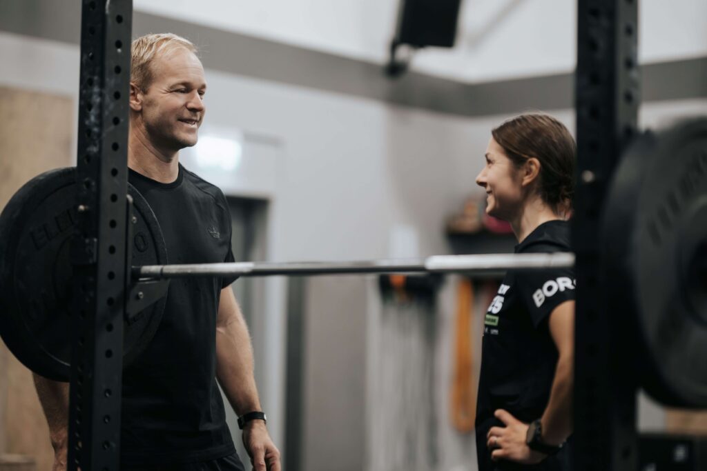 Man och kvinna pratar. Skivstång framför dem.